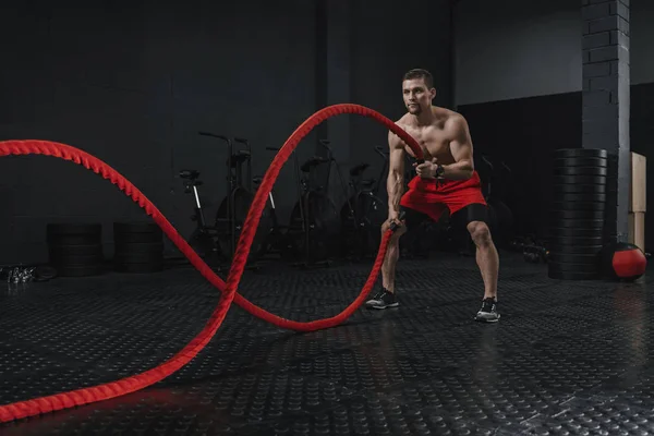 Mladý sportovec bitvy lana cvičení v tělocvičně crossfit — Stock fotografie