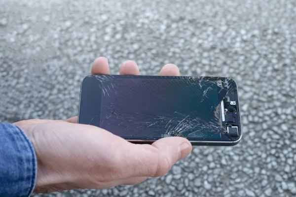 Smartphone with a broken screen glass in hand of young man