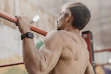 Gömleksiz atlet smartw ile horisontal pull-up egzersiz yapıyor