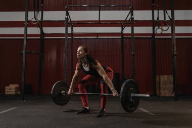Young female athlete doing deadlift exercise. Strong woman lifti