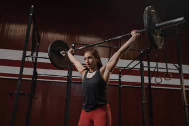 Young muscular woman doing weightlifting exercises at crossfit g