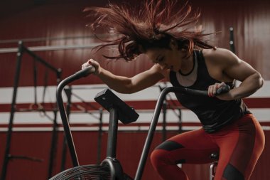 Crossfit kadın egzersiz bisikleti üzerinde yoğun kardiyo eğitim yapıyor.
