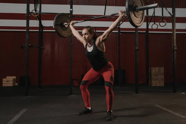 Pemuda crossfit atlet perempuan mengangkat beban berat barbel di — Stok Foto