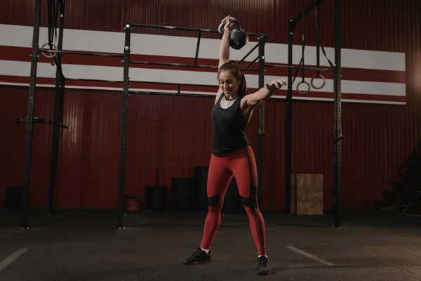 Crossfit mulher segurando um kettlebell sobrecarga e sorrindo enquanto c — Fotografia de Stock