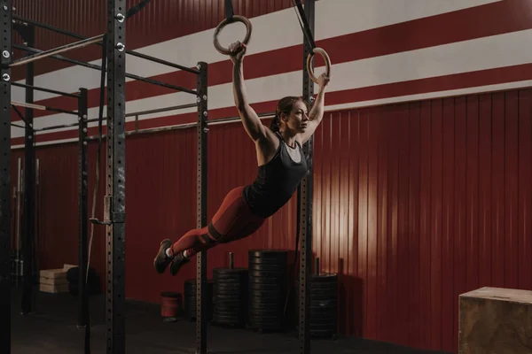 Jeune femme crossfit balançant sur des anneaux de gymnastique . — Photo