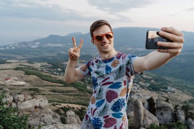 Neşeli mutlu adam zafer işareti yapıyor ve gülümsüyor.