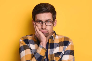 Gözlüklü, sıradan tişörtlü, yanaktan el ele tutuşan, yorgun ve hasta görünümlü, sarı duvarın üzerinde soyutlanmış genç adam. Çok çalışan serbest çalışan, işten sonra yorgun düşen bir öğrenci. Duygular ve tepki konsepti