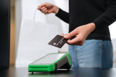Kablosuz ya da temassız ödemeyi kredi kartıyla yapan kadın müşterinin eli, alışveriş yapan kız. NFC teknolojisi perakende dükkanında. Temassız ödeme kavramı