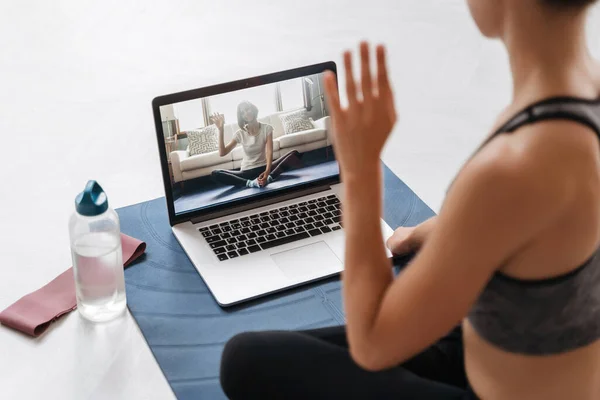 Spor giyim antrenörlüğünde genç fit kadın antrenörlere yakın çekim. Bilgisayarlı bir video konferansında online fitness eğitimi ya da sanal yoga dersi veriyorlar. Evde antrenman yapıyorum. Sağlık uygulaması ve sağlık konsepti 