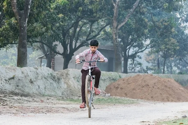 A teenager boy showing stunts with bicycle keeping front wheel in the air