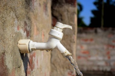 Güneşli bir gün ışığında beyaz su musluğundan akan su