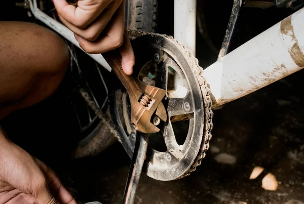 a hand tightening nut-bolts of a bicycle with metal wrench