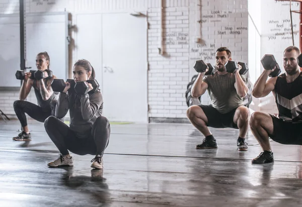 一群运动员和运动员在健身房蹲举重 — 图库照片