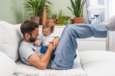 Mutlu oynayan beyaz adam gülümseyerek ve şirin bebek oğlu ile sarılma.