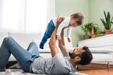 Yerde yatarken ve bebek oğlu ile oynarken mutlu beyaz adam.