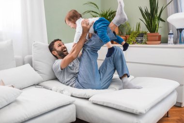 Happy smiling Caucasian man playing and cuddling with his cute baby son. clipart