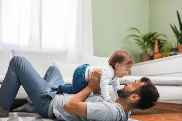 床に横になっていると 息子のかわいい赤ちゃんと遊んで幸せな白人男 — ストック写真