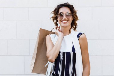 Alışveriş çantası tutarak ve kameraya bakıyor güzel şık beyaz kadın.