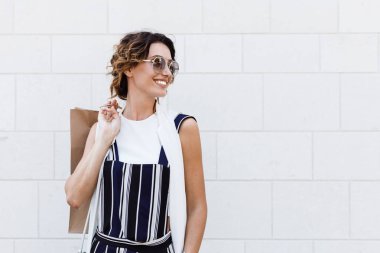 Alışveriş çantası tutarak ve mutlu görünüyordu güzel şık beyaz kadın.