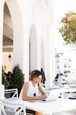 Kafede oturan ve onu laptop çalışma güzel gülümseyen beyaz kadın.