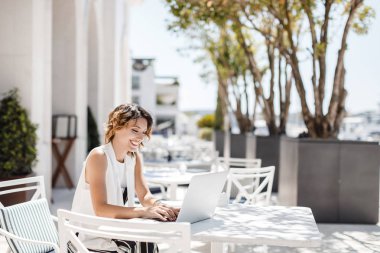Kafede oturan ve onu laptop çalışma güzel gülümseyen kafkas kadın beldedir.