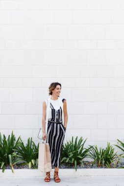 Güzel beyaz kadın holding alışveriş çantası gülümseyen ve açık havada duran.