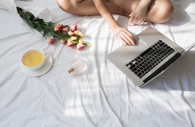 Sabahleyin yatağında oturmuş ve onu laptop yazarak unrecognisable kadın kırpılmış.