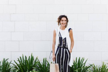 Güzel beyaz kadın holding alışveriş çantası gülümseyen ve kameraya bakıyor.