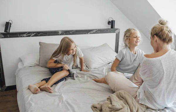 母と彼女の子供パジャマでキングサイズのベッドの上に座っていると 幸せそうに見えて — ストック写真