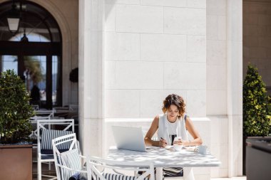 Kahve dükkanında oturma ve çalışma güzel gülümseyen beyaz kadın.