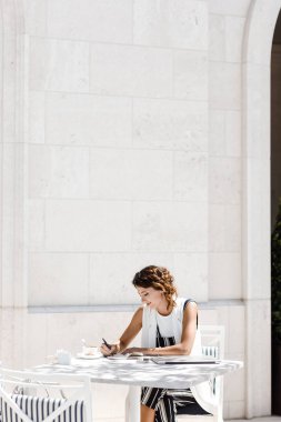 Kahve dükkanında oturmuş ve onun not defterinde yazma oldukça beyaz kadın.