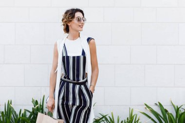 Kadın holding alışveriş çantası gülümseyen ve açık havada duran güzel şık beyaz.