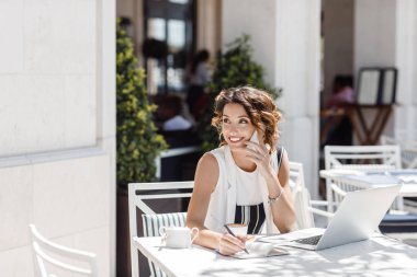 Onu cep telefonundan konuşuyor ve kahve dükkanında çalışan güzel şık gülümseyen beyaz bir kadın.