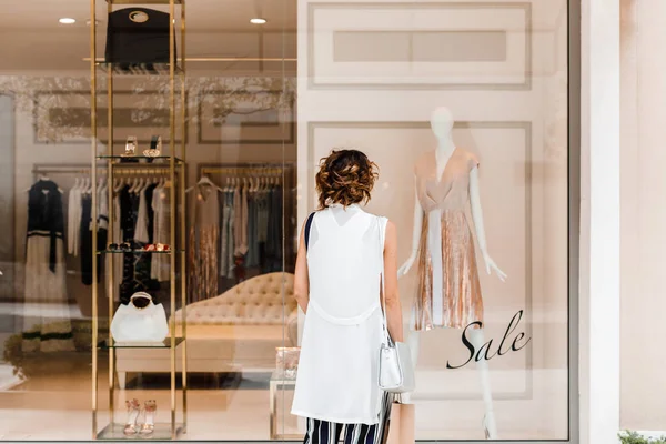 店の窓の前に立っている女性の買い物客の背面図 — ストック写真