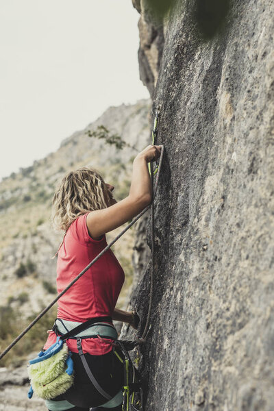 Female rock climber climbing outoors.