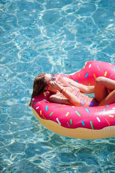 Pretty woman lying on floating ring on Mediterranean sea and enjoying sunbathe.