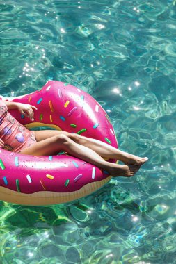 Bacaklar üzerinde pembe halka yalan ve denizde yüzen kırpılmış unrecognisable kadın.