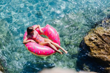 Güzel kadın Akdeniz ve zevk üzerinde kayan halka yatan güneşlenmek.