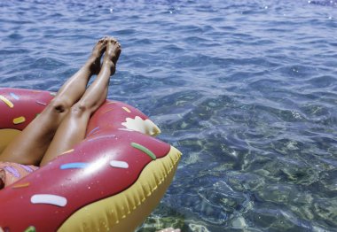 Halka yalan ve denizde yüzen kırpılmış unrecognisable kadın bacakları.