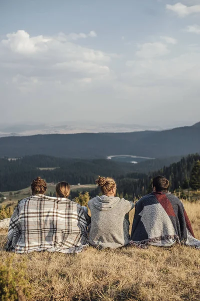 景色を楽しみながら自然に座っている若い人たちのグループの背面図 — ストック写真