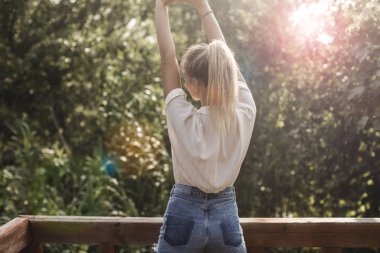 Teras üzerinde duran ve ellerini uzanan Genç kadın tayyare arkadan görünüm.