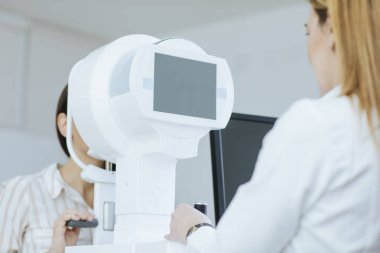 Bir kadın doktor hastasını için göz hastalıkları onay yapıyor.