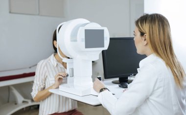 Bir kadın doktor hastasını için göz hastalıkları onay yapıyor.