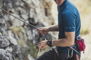 Bir adam dağcı dağın kaya tırmanışı için hazırlanıyor.