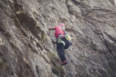 Bir kadın dağcı dağın kaya tırmanışı.