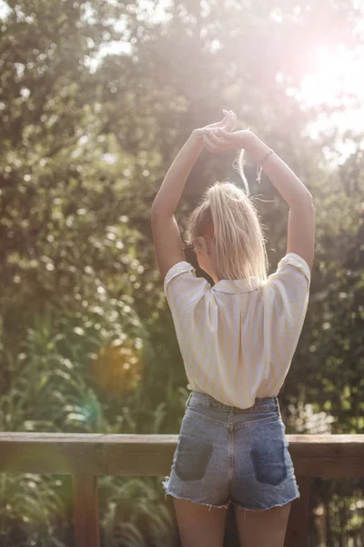 Teras üzerinde duran ve ellerini uzanan Genç kadın tayyare arkadan görünüm.