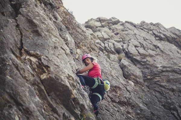 A woman mountaineer climbing a mountain rock.