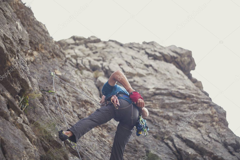 From below photo of a man climber climbing a rock.