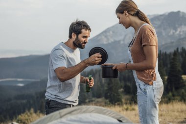Bir adam ve bir kadın kamp stading açık havada ve pot seyir.