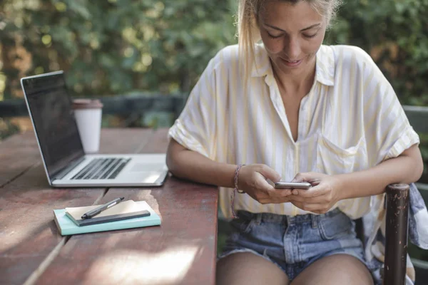 若い白人女性テラスに座って 彼女のスマート フォンで入力 — ストック写真